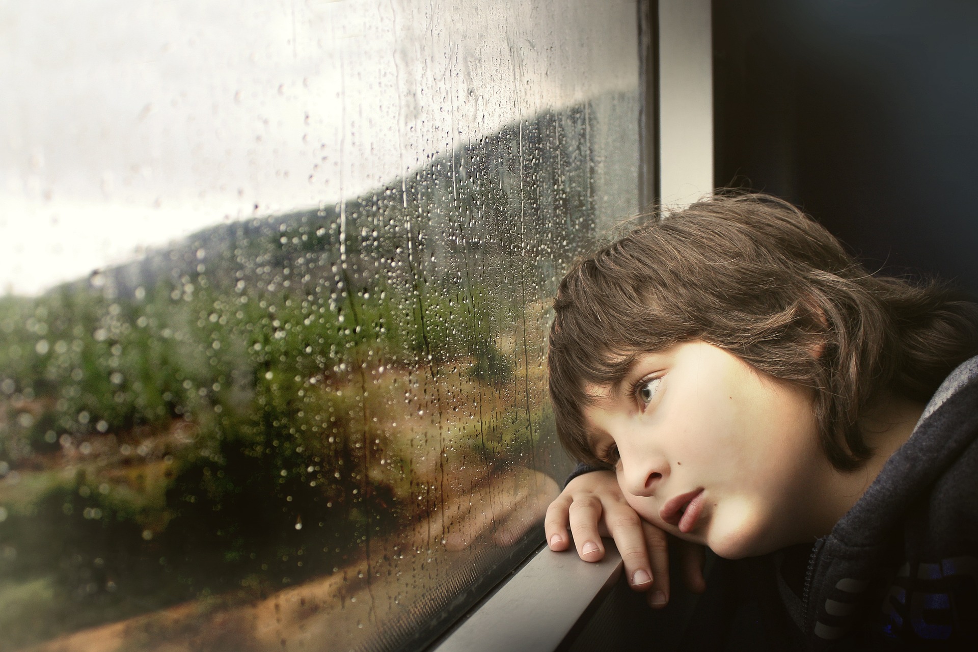 Trauriges Kind schaut aus dem Fenster